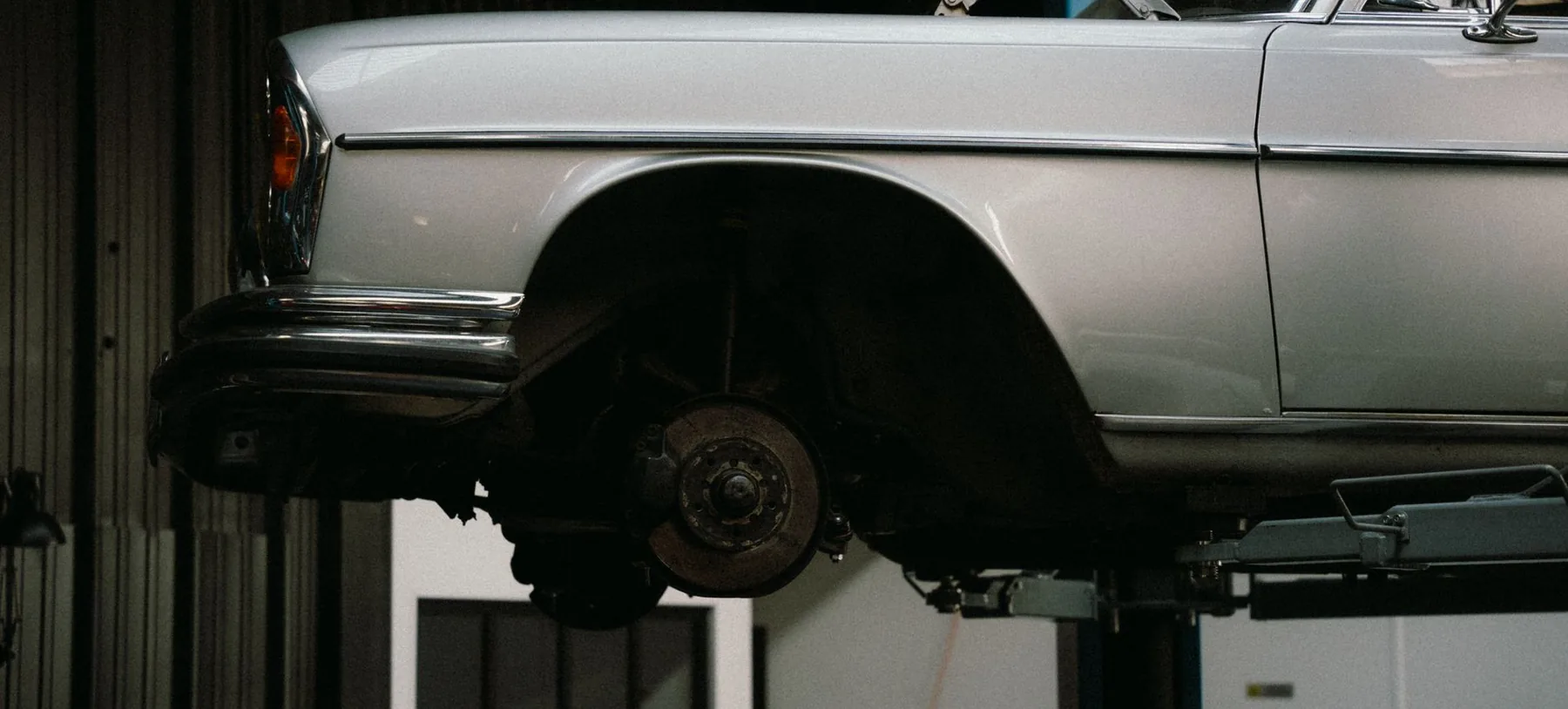 A car raised on a lift in a darkened service bay